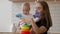 Little child girl and her mommy play with color toys at home