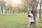 Little child girl reading book in summer park outdoor standing lean against tree trunk with looking to sky