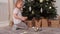 Little child girl removes toys stars balls from Christmas tree plays counts it.