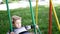 Little child girl rides on swings on playground