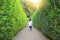 Little child girl running forward into garden Maze. Kid playing in labyrinth for fun and entertainment. Back view