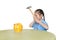 Little child girl in school uniform taking hammer trying to broke piggy bank isolated on white background at table. Schoolgirl