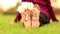 Little child girl sits on grass with painted feet with funny comic faces