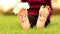 Little child girl sits on grass with painted feet with funny comic faces