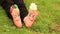 Little child girl sits on grass with painted feet with funny comic faces