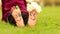 Little child girl sits on grass with painted feet with funny comic faces
