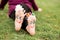 Little child girl sits on grass with painted feet with funny comic faces