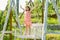 Little child girl is swinging on a swing in summer park. Sunny joyful summer day. Child swinging on playground on sunny