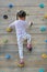 Little child girl trying on free climbing on the playground wooden wall outdoors