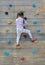 Little child girl trying on free climbing on the playground wooden wall outdoors