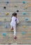 Little child girl trying on free climbing on the playground wooden wall outdoors