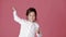 Little child girl in white shirt dancing on pink background.