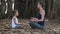 Little child girl with young mother meditating together under banyan tree
