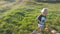 Little child goes at the field to his father, lying on green grass and sit on his back. Happy family on a summer meadow