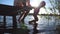 Little child and his dad swinging feet in the water on sunny day. Young dad sitting on the edge of wooden jetty at lake