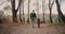 Little child and his mother are walking together at forest, holding hands, back view, family rest at autumn day
