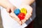 Little child holding three colorful wooden dice showing six in her small hands, closeup. Multi colored game dice with number 6