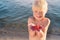 Little child holds starfish on his palm. Blond boy smiles and shows large starfish