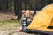 Little child installing camping tent and looking