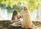 Little child with Labrador retriever dog sitting in sunny summer