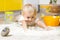 Little child laying on very messy kitchen floor