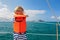 Little child in life jacket on board of sailing boat