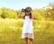 Little child looks in binoculars outdoors in sunny summer day