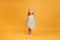 A little child measures her height on a yellow background. Concept of development, goal, success