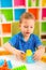 Little child playing with lots of colorful plastic blocks indoor