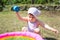 Little child playing with water close to small inflatable pool, sunny weather, house backyard