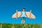 Little child plays astronaut or pilot. Child on the background of blue sky. Kids with paper wings jetpack dreams