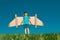 Little child plays astronaut or pilot. Child on the background of blue sky. Kids with paper wings jetpack dreams