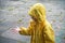 Little child in raincoat playing with raindrops