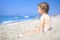Little child on sandy beach of sea looking at waves. Child on the sea on clear sunny day. Relax on the beach