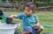 Little child shovels soil into pots to prepare plants for planting. Toddler boy digging soil for planting to Mother`s little