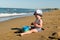 little child sits and plays by the sea with a bucket