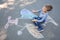 Little child sitting near chalk drawing of airplane
