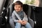 Little child sitting in safety seat inside car. Danger prevention