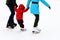 Little child skates with his parents at the ice rink in winter. A man and woman is teaching her child to skate. Sports clubs