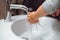 Little child, small one year old baby washing and trying to wash hands with soap dispenser and tap water