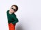 Little child in sunglasses, green jumper and orange pants. He is smiling while posing isolated on white studio background