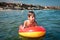 Little child swimming in sea on inflatable mattress and looking with caution