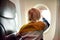 Little child traveling by an airplane. Preschooler boy looking at the aircraft window during the flight. Air travel with kids