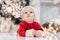 Little child under Christmas tree. baby boy in Santa Claus hat with gifts under Christmas tree with many gift boxes presents