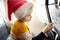 Little child wearing Santa Claus hat traveling by an airplane. Preschooler boy having fun during flight. Family trip for winter