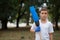 A little child in a white T-shirt standing with a blue broom on a blurred natural background. Ecology, pollution concept