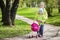 Little children, brother and sister play in the yard with a toy Baby carriage. Children playing in the green park in the spring