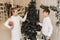 Little children decorate the Christmas tree in a bright interior. Girl and boy, brother and sister hang New Year`s toys