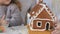 Little children decorates a gingerbread house with a colorful candies