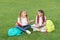 Little children girls read books sit on grass, summer school concept